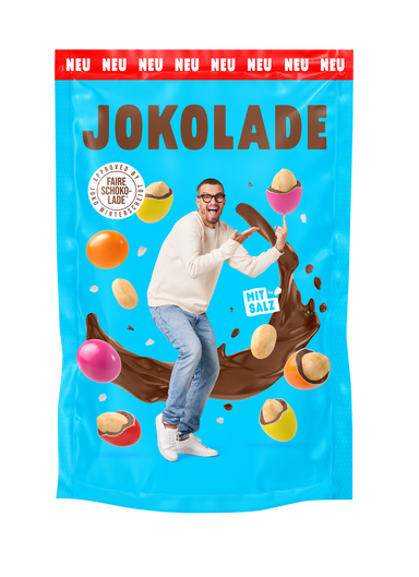 Produktverpackung (blau): JOKOLADE Peanuts mit Salz. Joko Winterscheidt steht in der Mitte und zeigt auf eine dragierte Erdnuss. Hintergrund: "fliegende" dragierte Erdnüsse. Button: Approved by Joko Winterscheidt. Faire Schokolade. Banderole oben: rot: NEU