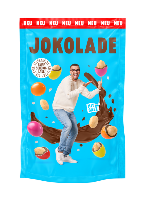 Produktverpackung (blau): JOKOLADE Peanuts mit Salz. Joko Winterscheidt steht in der Mitte und zeigt auf eine dragierte Erdnuss. Hintergrund: "fliegende" dragierte Erdnüsse. Button: Approved by Joko Winterscheidt. Faire Schokolade. Banderole oben: rot: NEU
