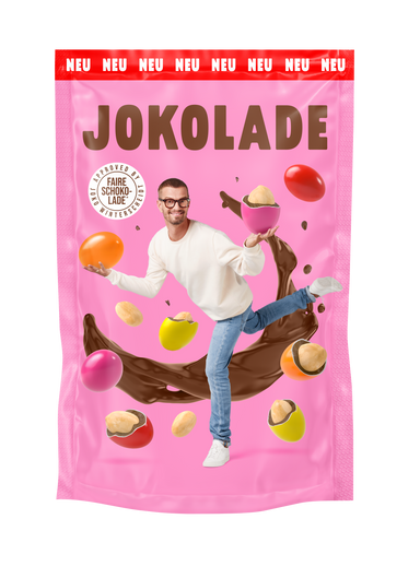 Produktverpackung (rosa): JOKOLADE Peanuts mit Salz. Joko Winterscheidt steht in der Mitte und balanciert dragierte Erdnüsse. Hintergrund: "fliegende" dragierte Erdnüsse. Button: Approved by Joko Winterscheidt. Faire Schokolade. Banderole oben: rot: NEU